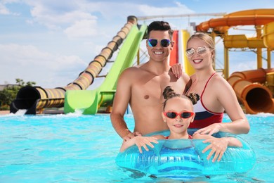 Photo of Happy family with inflatable ring in swimming pool at water park, space for text