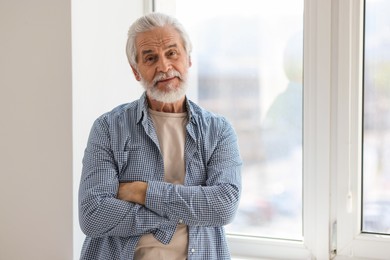 Photo of Portrait of happy grandpa with grey hair near window indoors