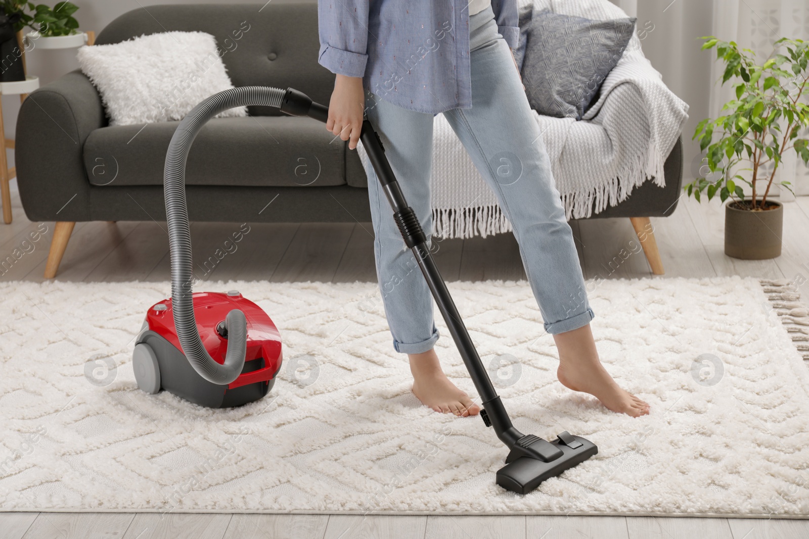 Photo of Woman cleaning carpet with vacuum cleaner at home, closeup