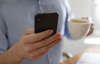 Photo of Man with smartphone indoors, closeup of hand