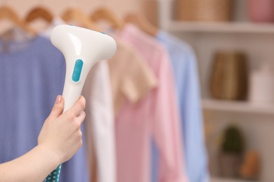 Woman with modern steam iron at home, closeup. Space for text