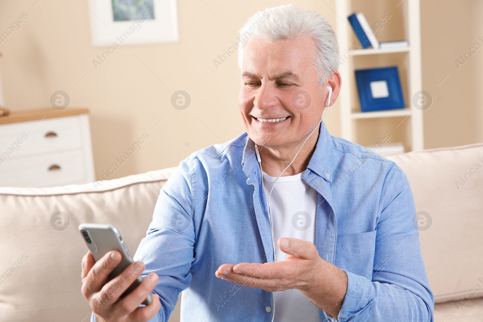 Photo of Mature man using video chat on mobile phone at home