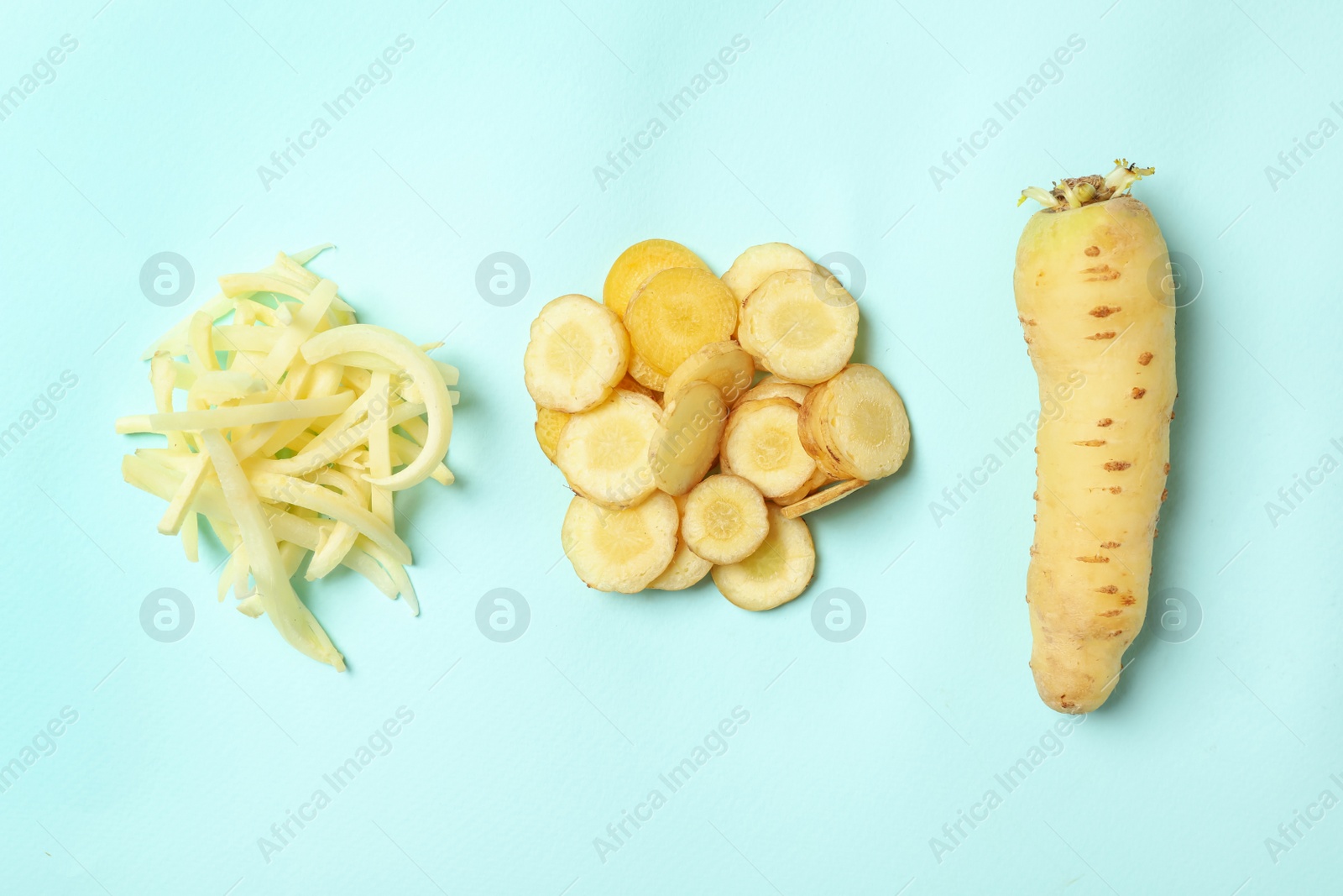 Photo of Whole and cut raw white carrots on light blue background, flat lay