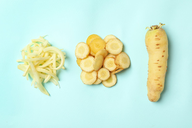 Photo of Whole and cut raw white carrots on light blue background, flat lay