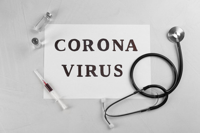 Paper with words CORONA VIRUS and stethoscope on light background, flat lay