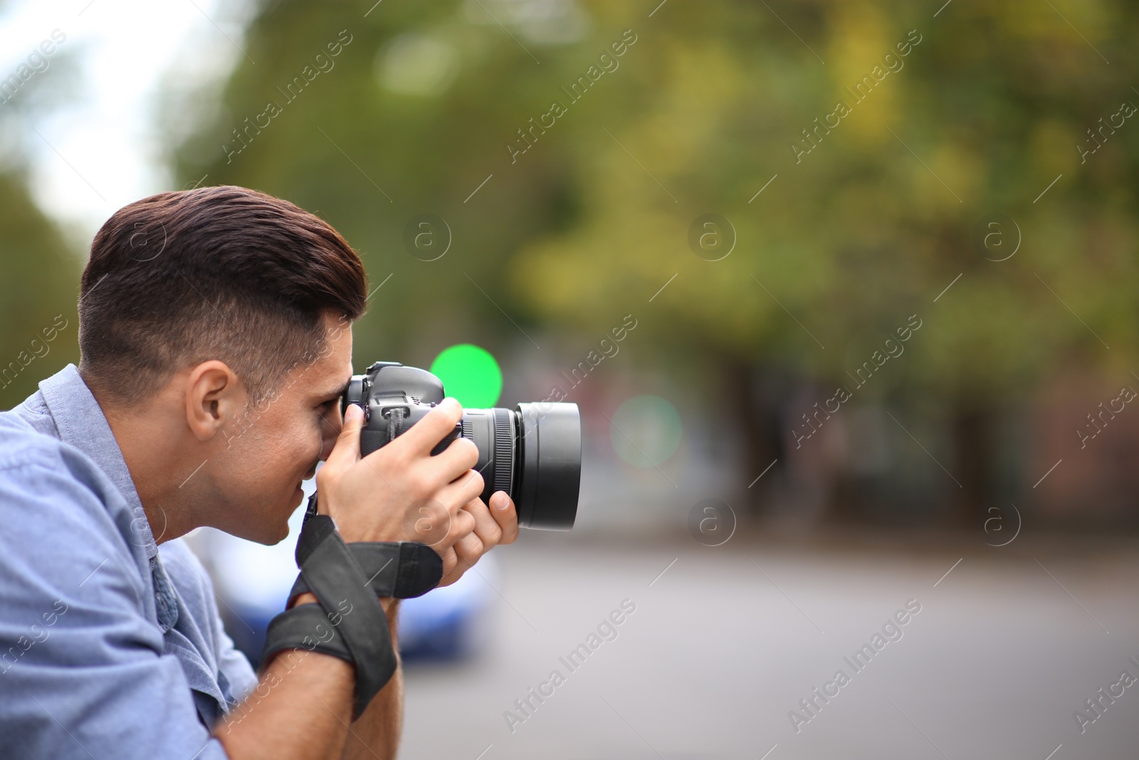 Photo of Photographer taking picture with professional camera on city street