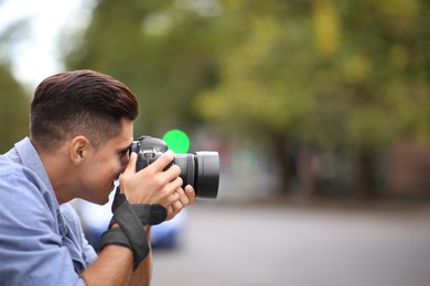 Photographer taking picture with professional camera on city street