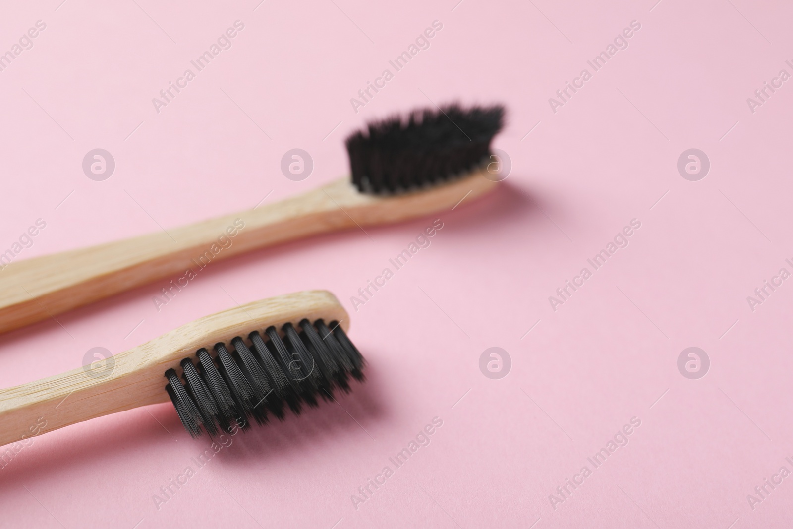Photo of Two bamboo toothbrushes on pink background, closeup. Space for text