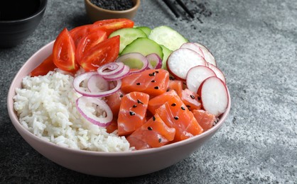 Delicious poke bowl with salmon and vegetables served on grey table