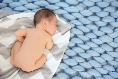 Photo of Adorable newborn baby sleeping on soft plaid, top view