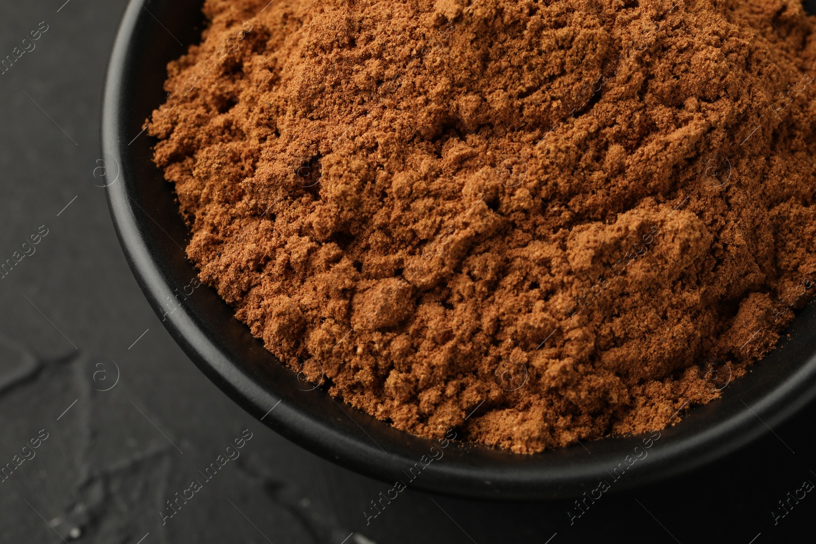 Photo of Aromatic cinnamon powder on black table, closeup