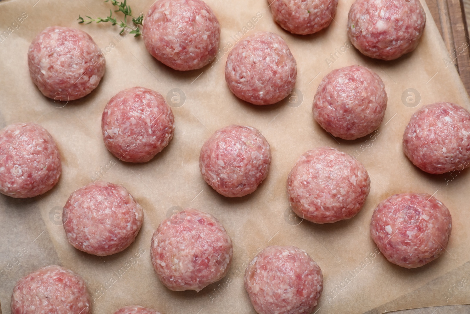 Photo of Many fresh raw meatballs on parchment paper, flat lay