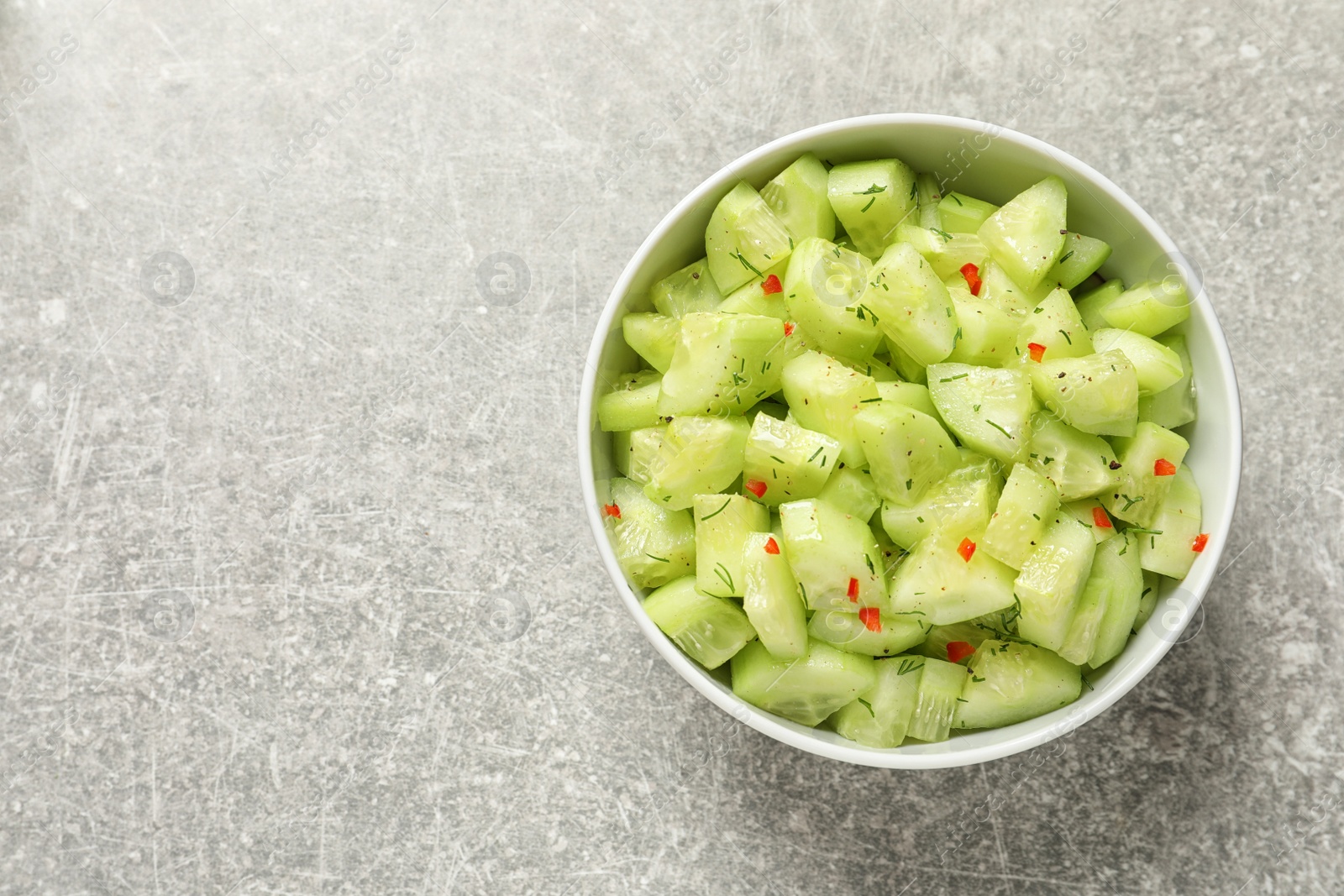 Photo of Delicious cucumber salad in bowl on grey background, top view. Space for text