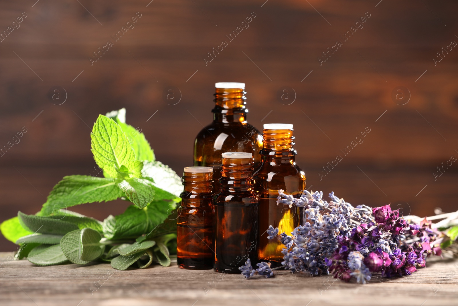 Photo of Bottles with essential oils, herbs and flowers on wooden table