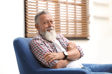 Photo of Portrait of handsome mature man sitting in armchair indoors