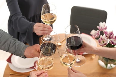 People with glasses of wine at table indoors, closeup