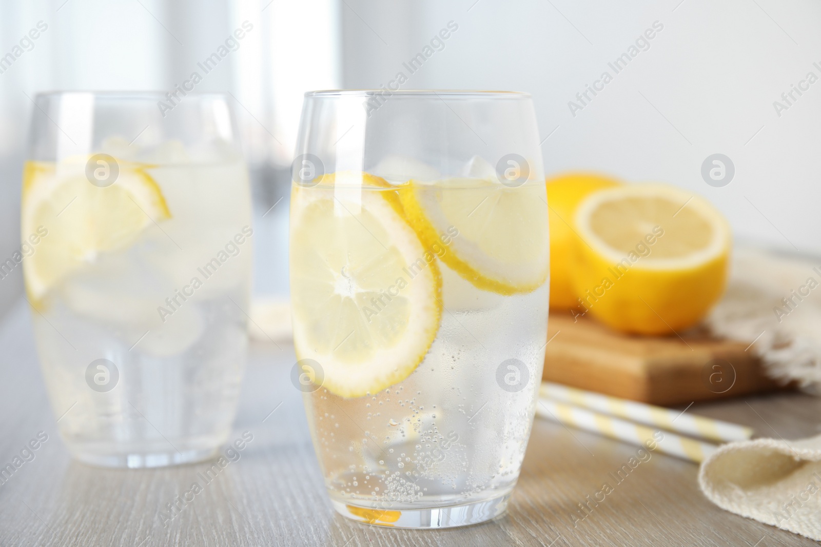 Photo of Soda water with lemon slices and ice cubes on wooden table indoors