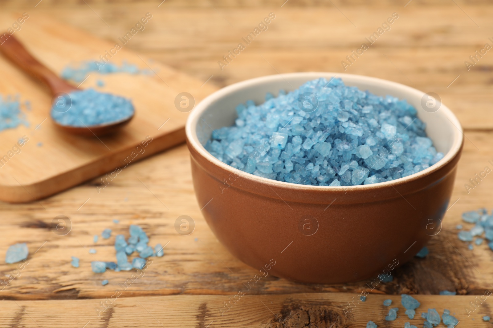 Photo of Bowl with blue sea salt on wooden table, closeup