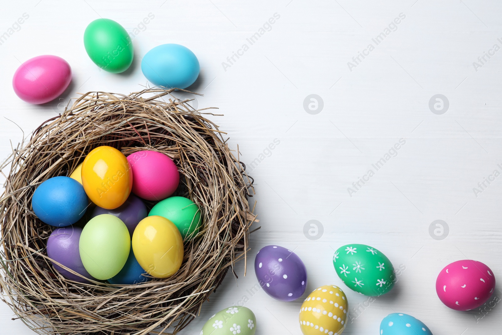 Photo of Bright painted eggs on white wooden table, flat lay with space for text. Happy Easter