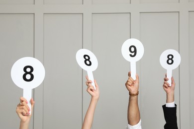 Panel of judges holding different score signs against light wall, closeup