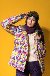 Photo of Woman wearing stylish winter sport clothes on yellow background