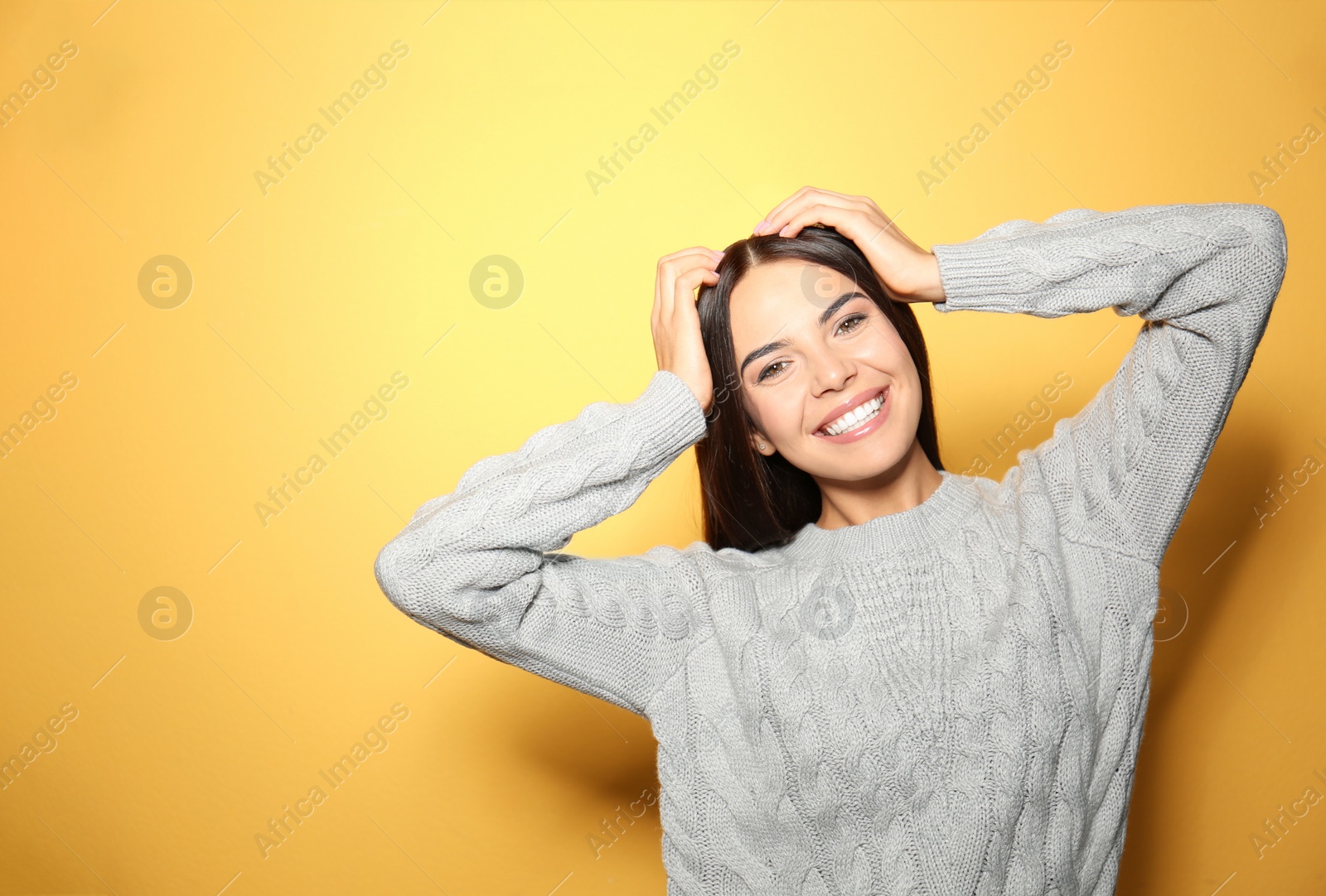 Image of Happy young woman wearing warm sweater on yellow background 