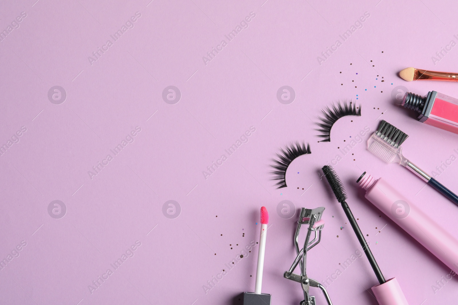 Photo of Flat lay composition with false eyelashes and other makeup products on pink background, space for text