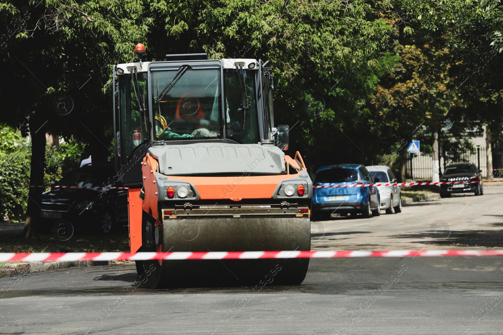 Image of Roller working on city street. Road repairing