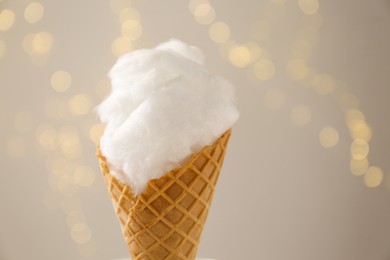 Photo of Sweet cotton candy in waffle cone against blurred lights, closeup