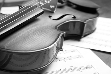 Image of Beautiful violin and note sheets on table, closeup. Black and white tone