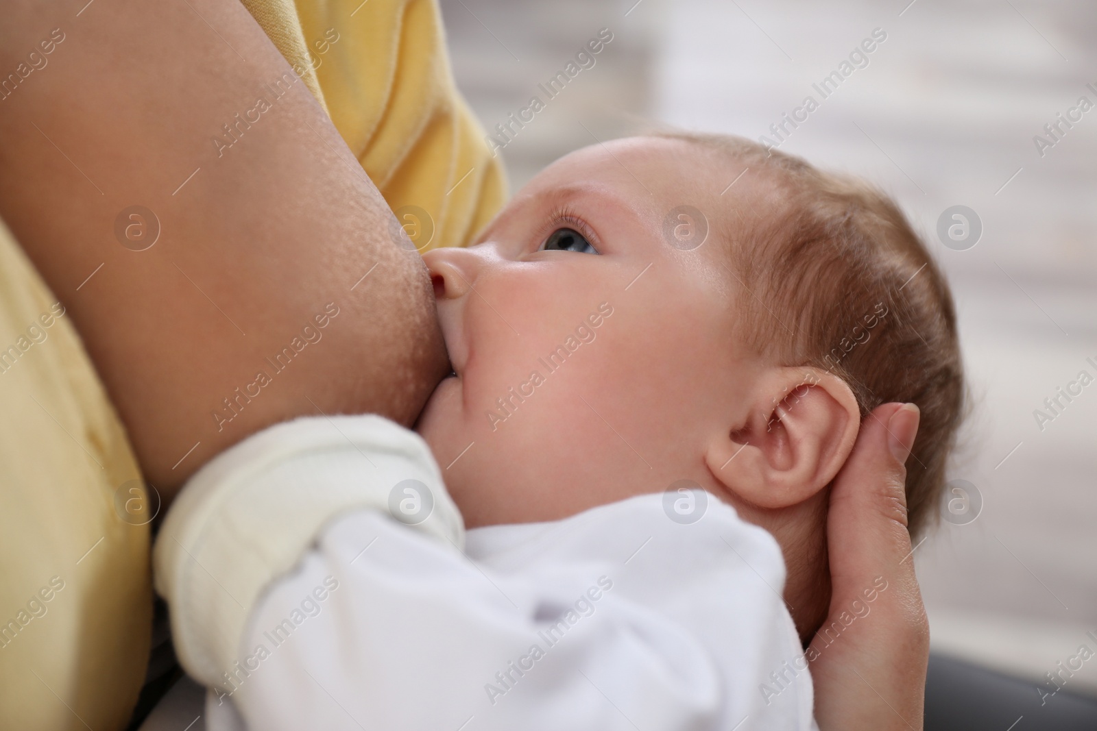 Photo of Young woman breast feeding her little baby at home, closeup