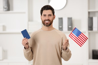 Immigration. Happy man with passport and American flag indoors
