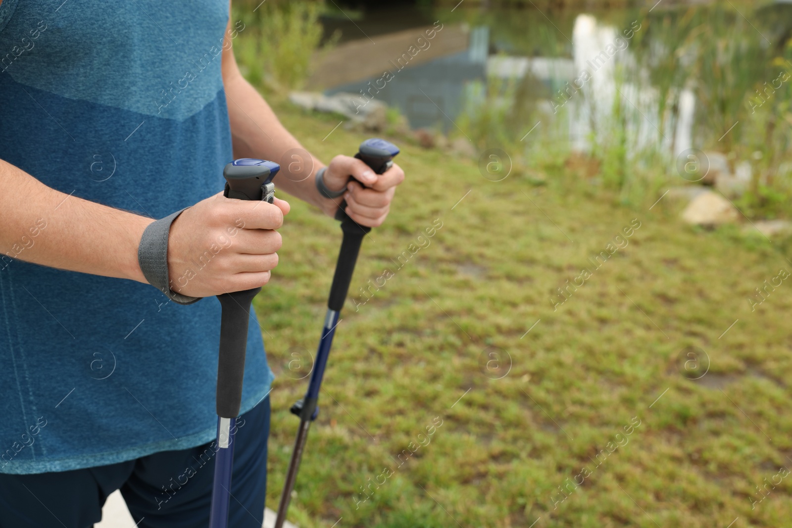 Photo of Man practicing Nordic walking with poles outdoors, closeup. Space for text