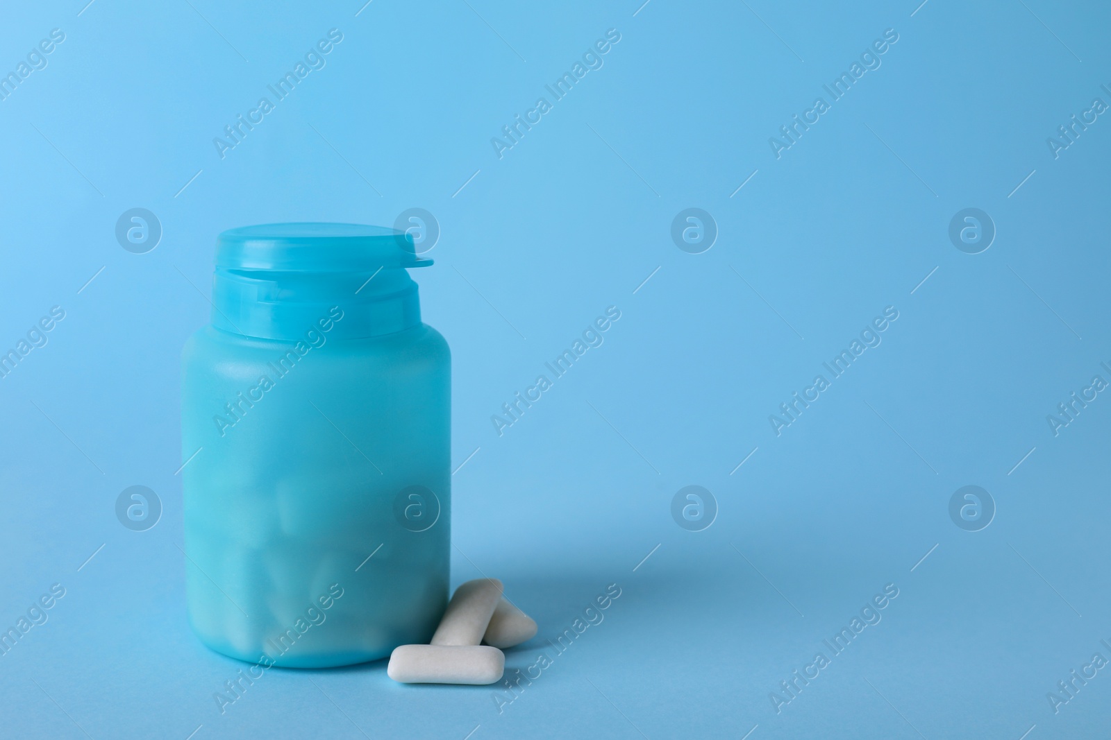 Photo of Jar with chewing gums on light blue background. Space for text