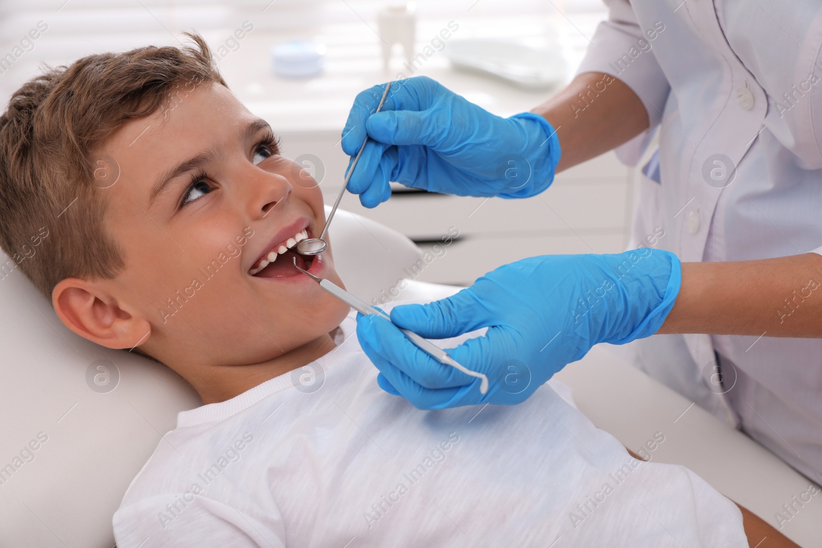 Photo of Dentist examining little boy's teeth in modern clinic