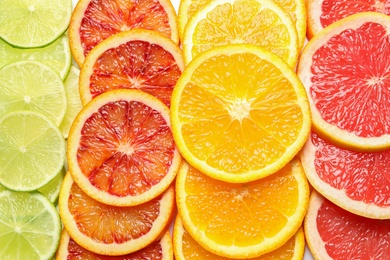 Photo of Slices of fresh citrus fruits as background, top view