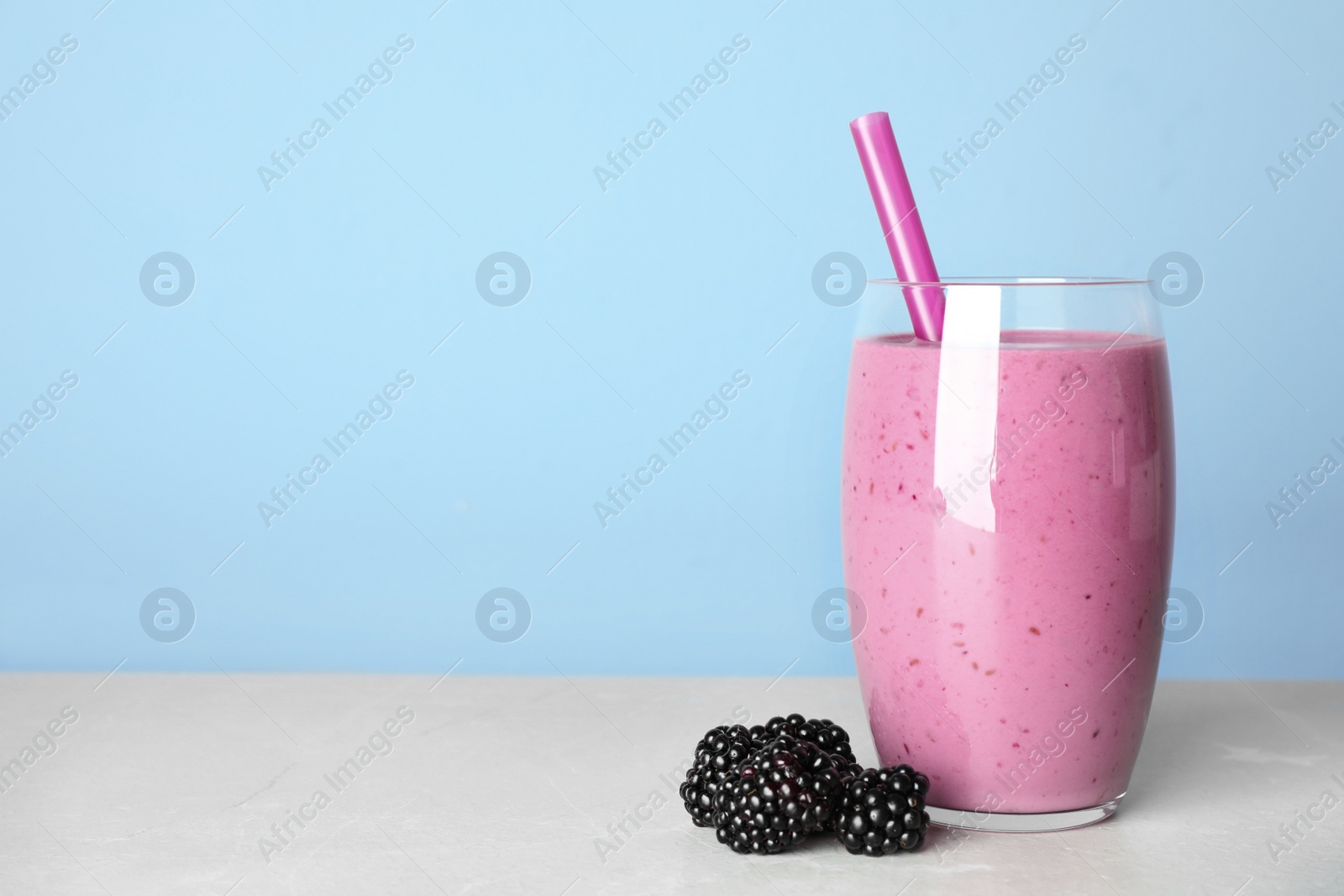 Photo of Delicious blackberry smoothie in glass on light table