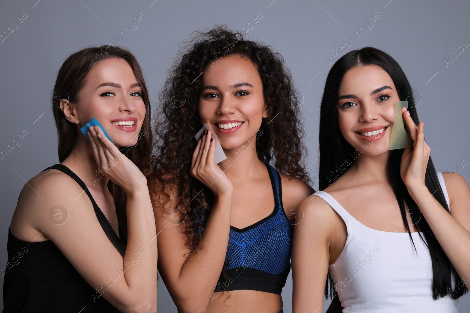 Photo of Beautiful women using mattifying wipes on grey background