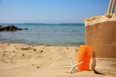 Photo of Sunscreen, starfish and bag on beach, space for text. Sun protection care