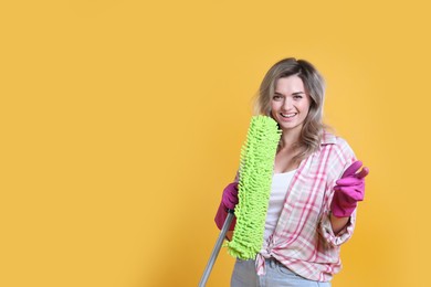 Photo of Beautiful young woman with mop singing on orange background. Space for text