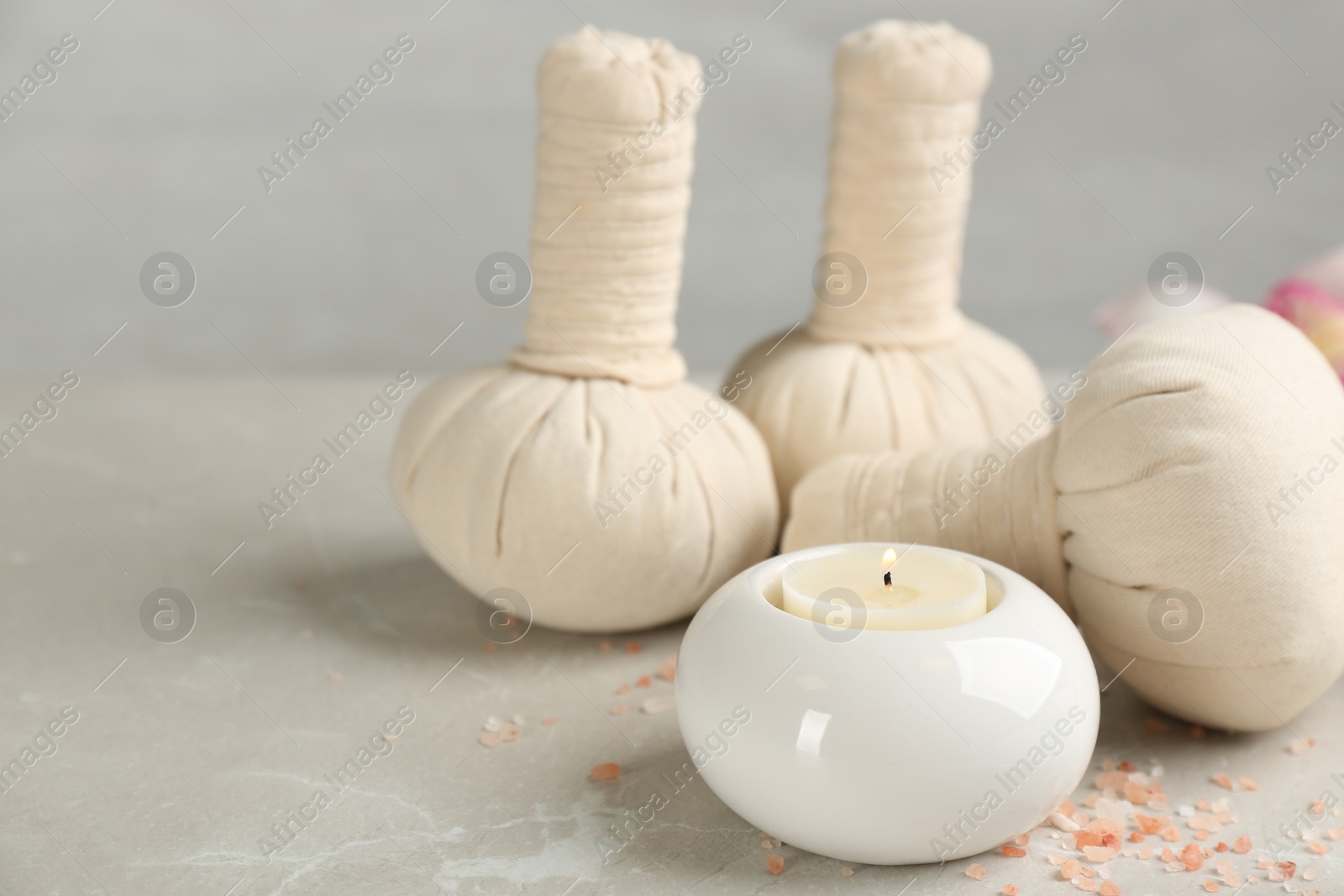 Photo of Beautiful composition with candle and spa herbal bags on marble table. Space for text
