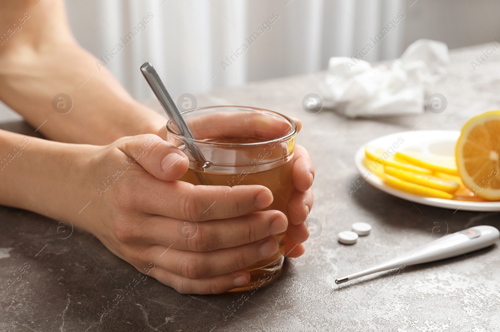 Photo of Woman holding glass with hot tea for cold on table