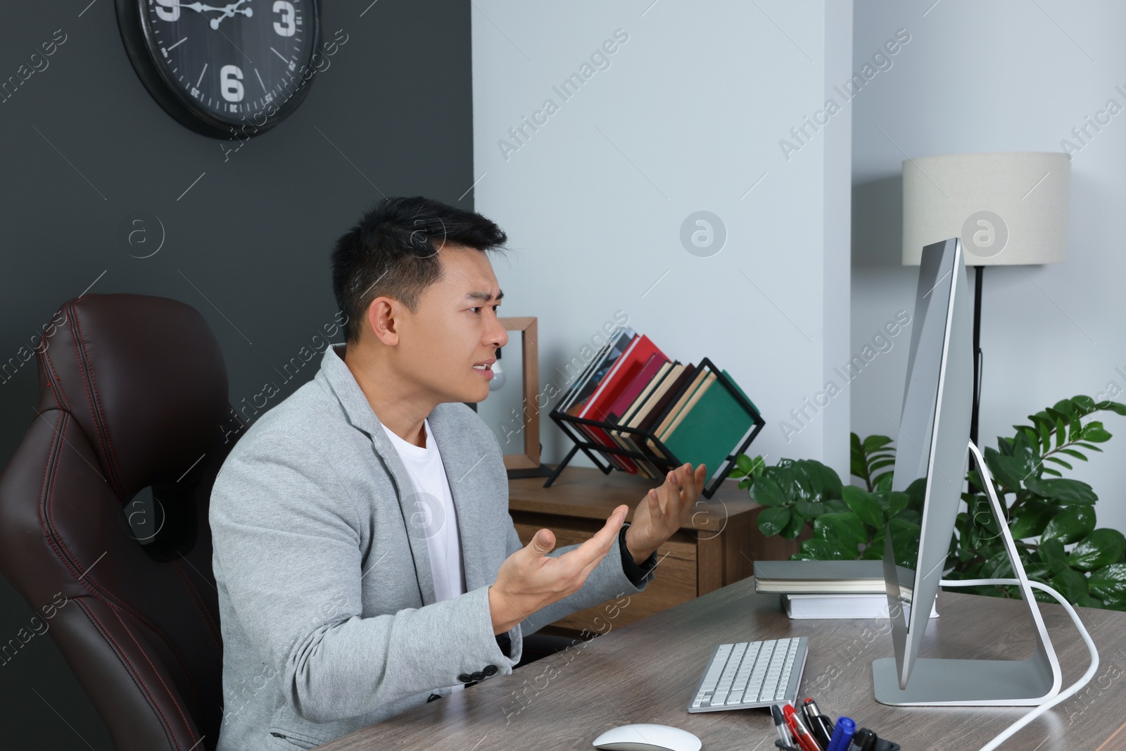 Photo of Angry boss having online meeting on computer at wooden table in modern office