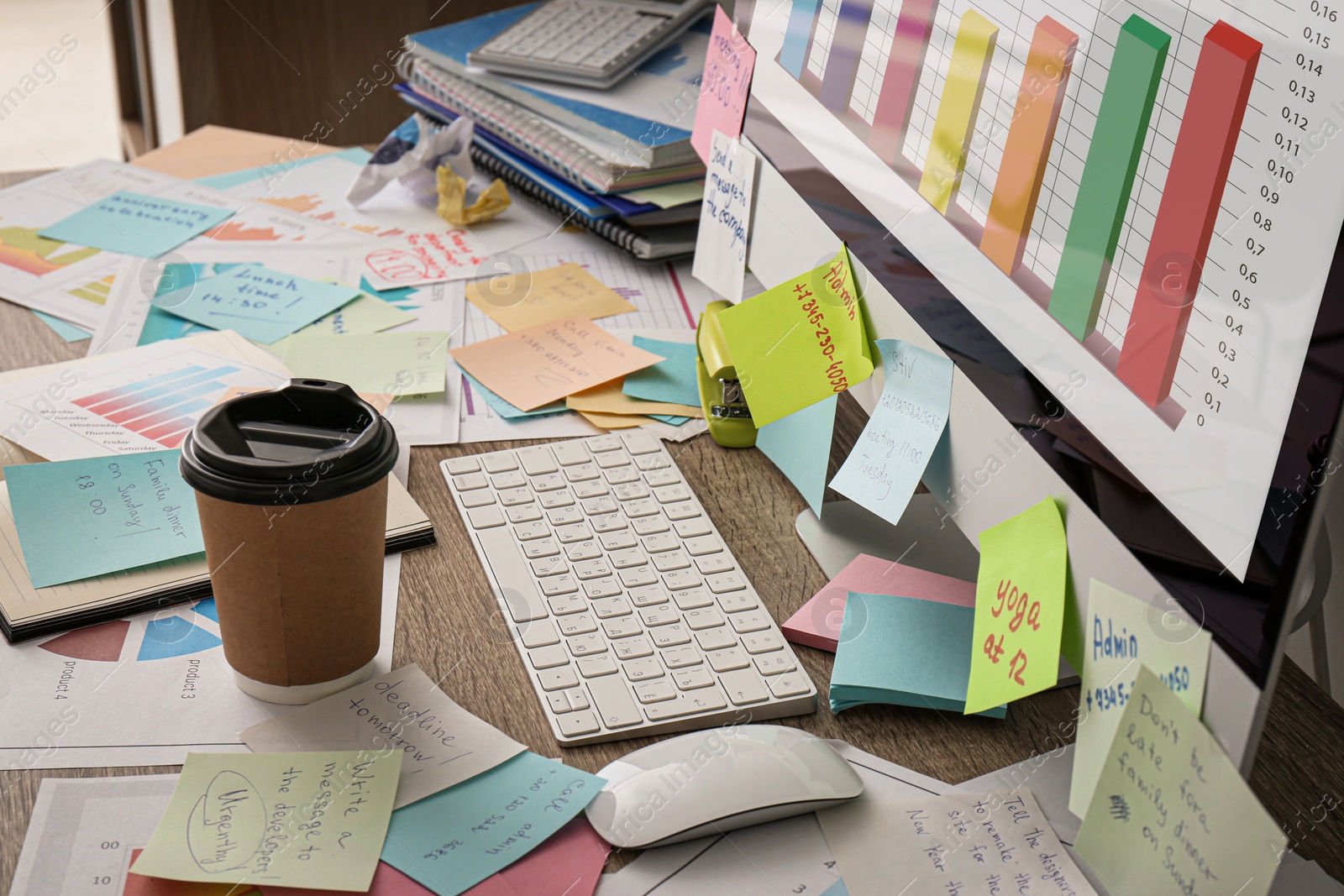 Photo of Computer, notes and office stationery in mess on desk. Overwhelmed with work