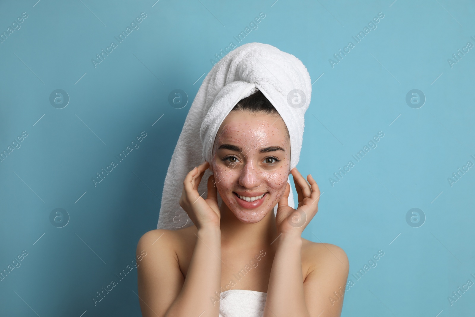 Photo of Woman with pomegranate face mask on light blue background