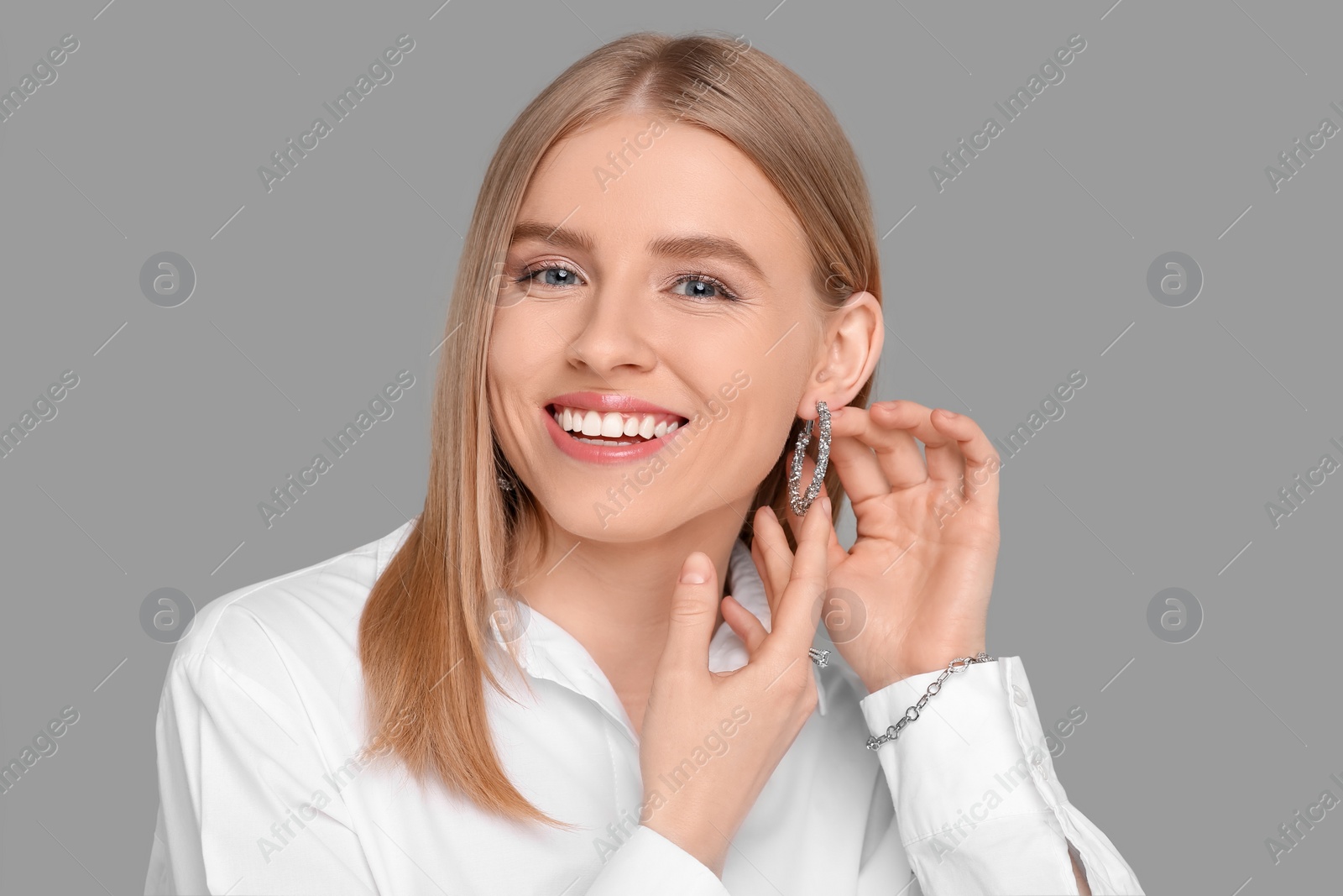 Photo of Beautiful young woman with elegant jewelry on gray background