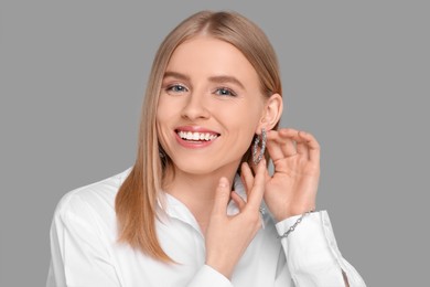 Photo of Beautiful young woman with elegant jewelry on gray background