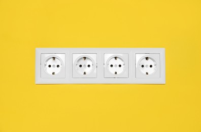 Photo of Power sockets on yellow wall. Electrical supply