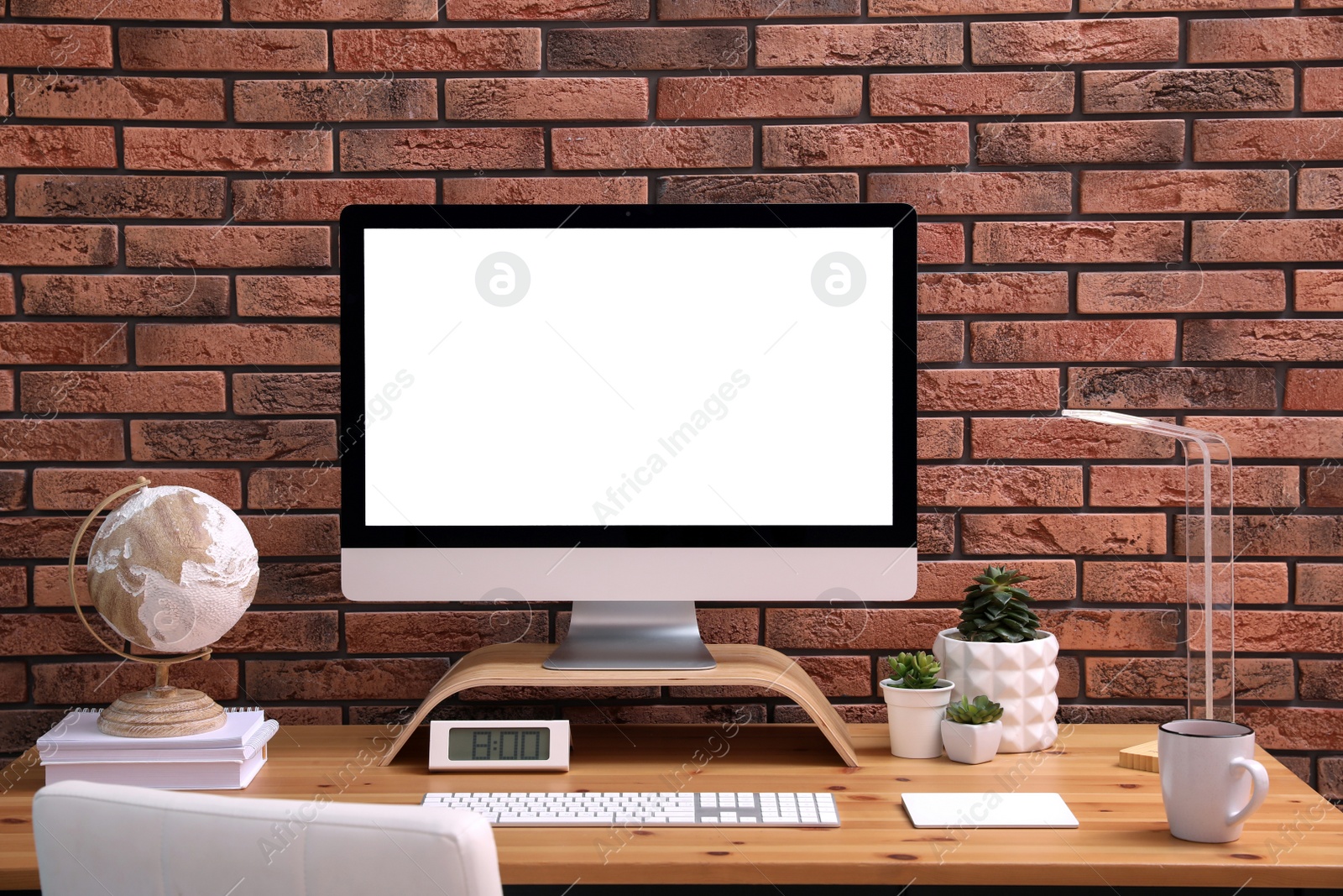 Photo of Stylish workplace with modern computer near brick wall indoors. Space for text