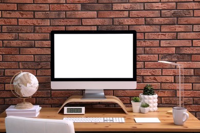 Photo of Stylish workplace with modern computer near brick wall indoors. Space for text
